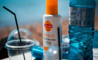 close up image of sunscreen, waterbottle and unknown items on a beach table